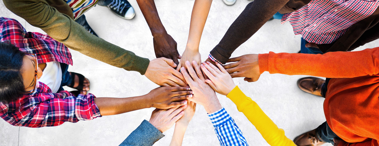 Zehn Menschen mit verschiedenen Hautfarben, halten die Hände im Kreis zusammen